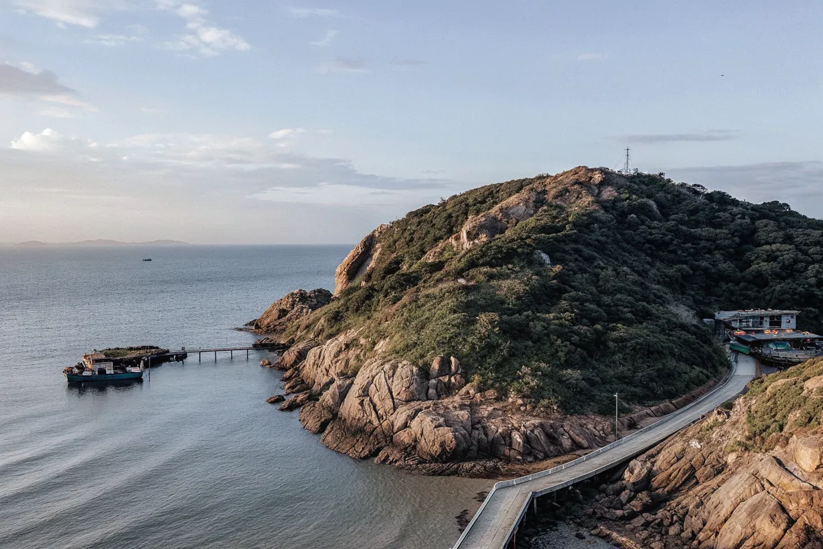 A green headland and a coastal road above a calm bay near Vung Tau